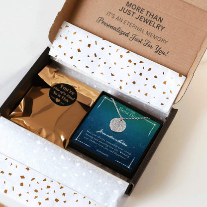 Personalized silver necklace with a coin pendant engraved in custom star map, packaging in a gift box with a festive greeting card for best dad and gold confetti paper, held by hands against a neutral background.