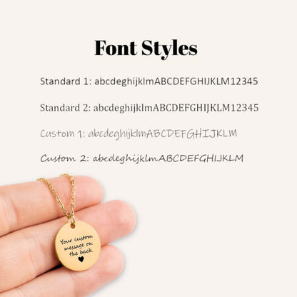 Gold necklace with a round pendant displaying customizable text on a white background with font styles options.