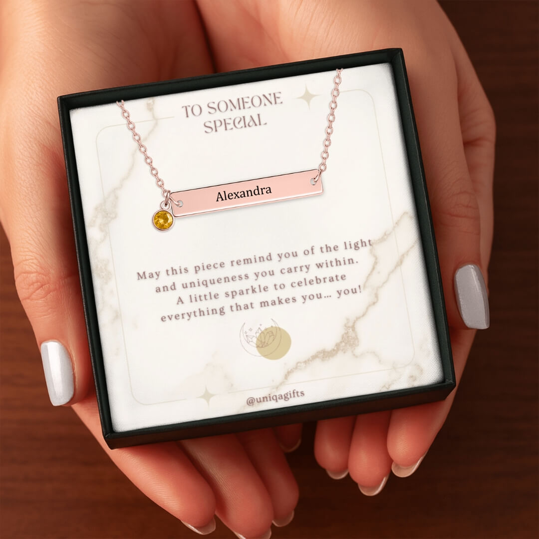 A woman hands holding birthstone necklace gift box over wood surface.