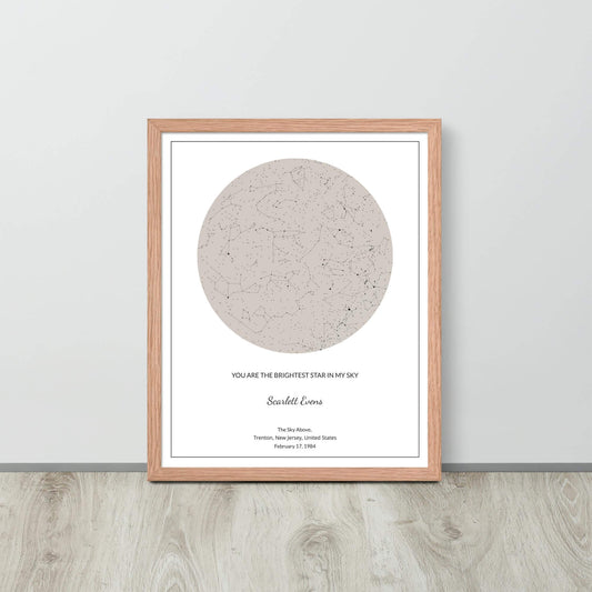 Soft Ambar custom star map poster in a wood frame leaning against a light-colored wall on a light wood floor.