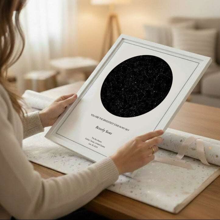woman holding a framed star map poster on a table with a wrapping paper in a cozy room.